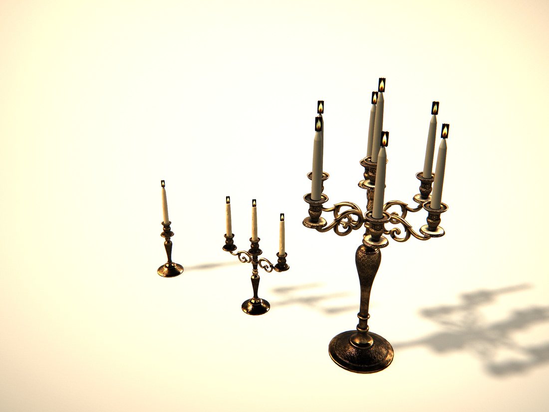 Two brass candleholders with white candles, the larger one in front.
